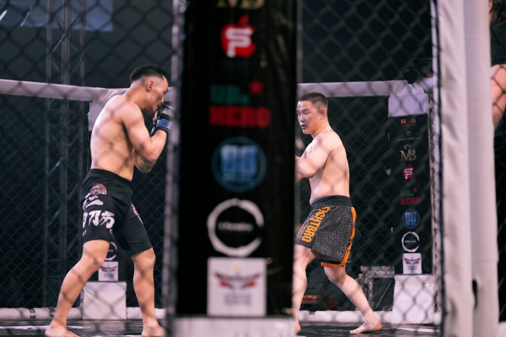 Two mixed martial arts fighters grapple inside an octagon cage during a bout.