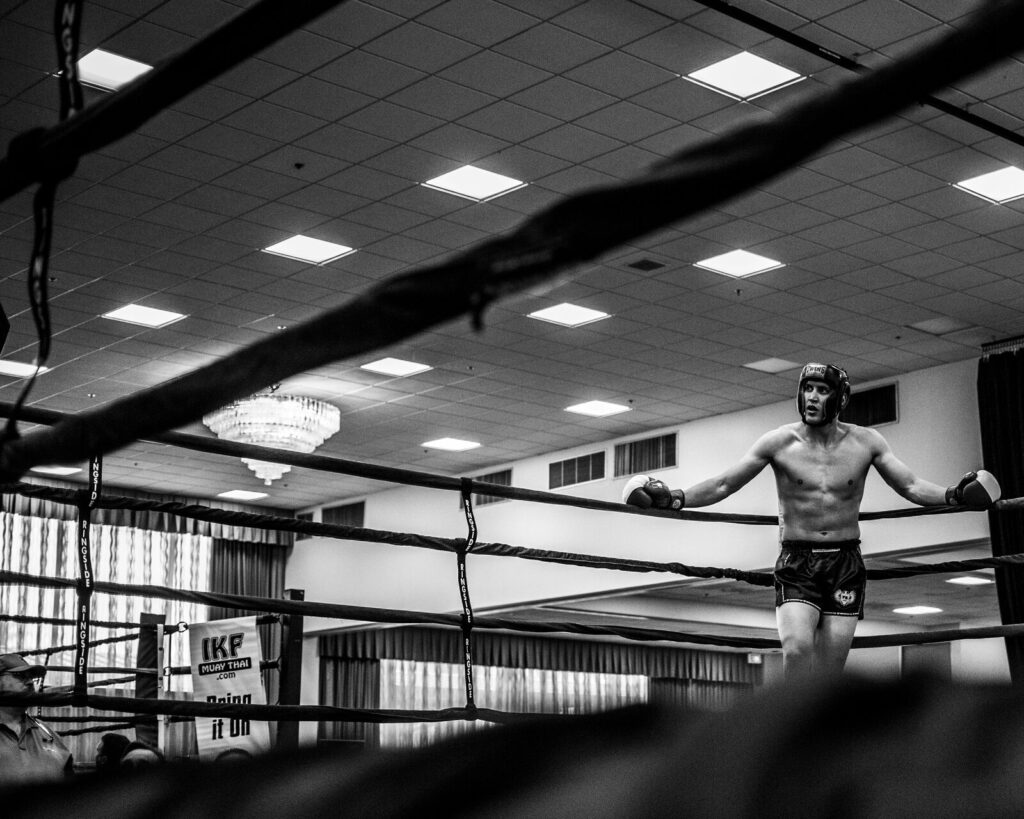 A boxer resting against the ropes in a boxing ring