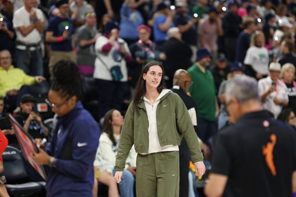 Caitlin Clark of the Indiana Fever walks on the court in warmup gear during a WNBA game.