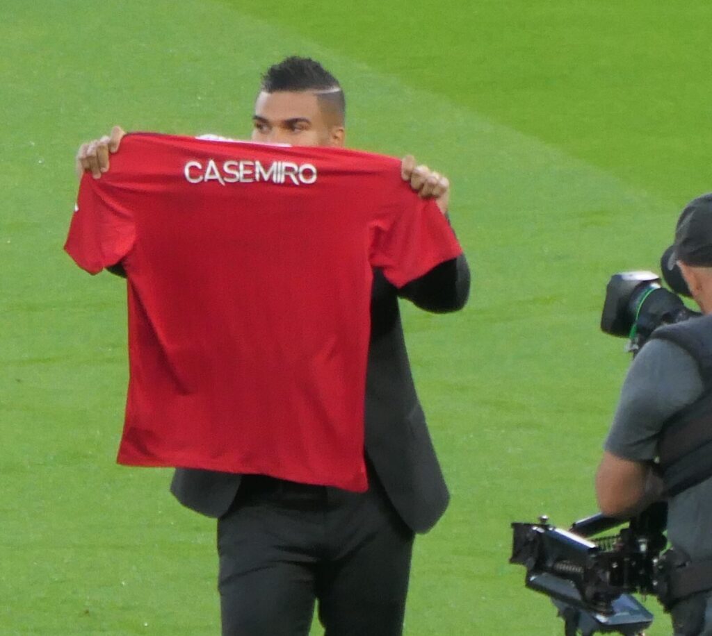 Casemiro holds up his Manchester United shirt on the pitch during his 2022 unveiling at Old Trafford.