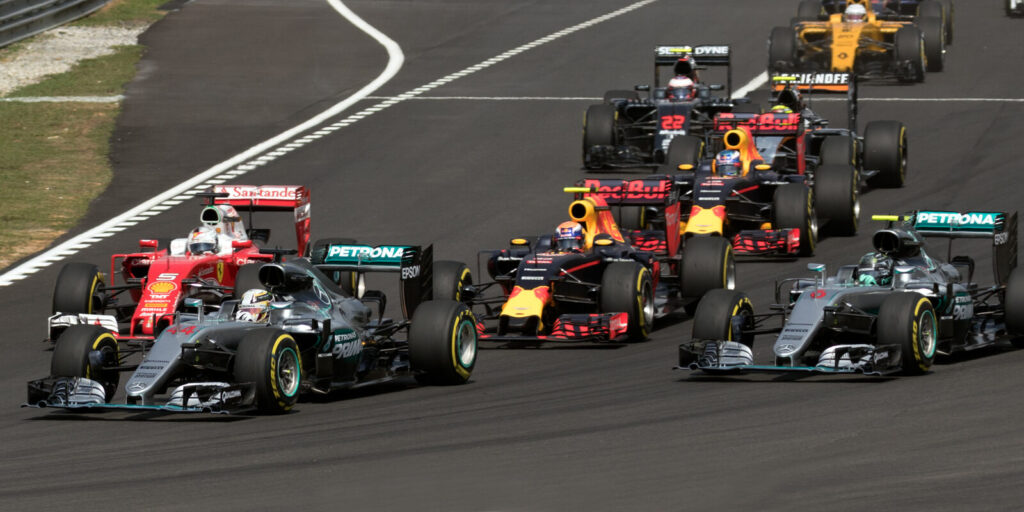Formula 1 cars racing side by side on the opening lap of a Grand Prix