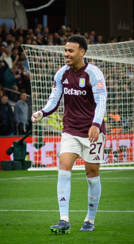 Morgan Rogers, wearing an Aston Villa kit, smiles on the pitch after scoring against Bologna in April 2026.