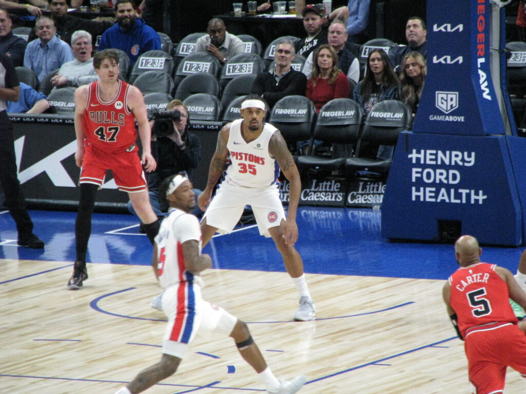 NBA players battle for position under the basket during a regular-season game at Little Caesars Arena in Detroit.