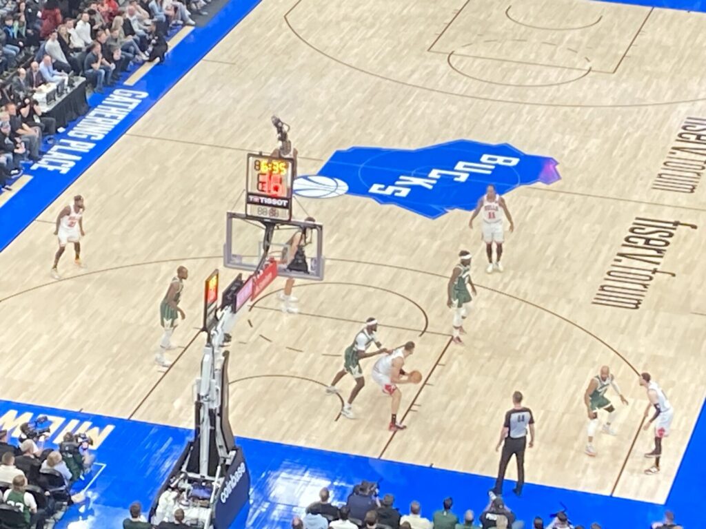 NBA player attacking the rim while defended by a Milwaukee Bucks player at Fiserv Forum