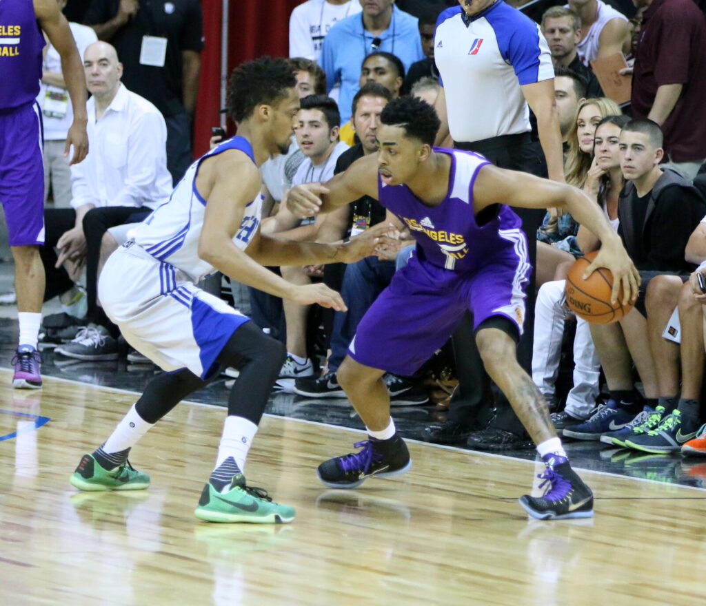 An NBA Summer League player in a purple jersey drives the ball past a defender in white on the court in Las Vegas.
