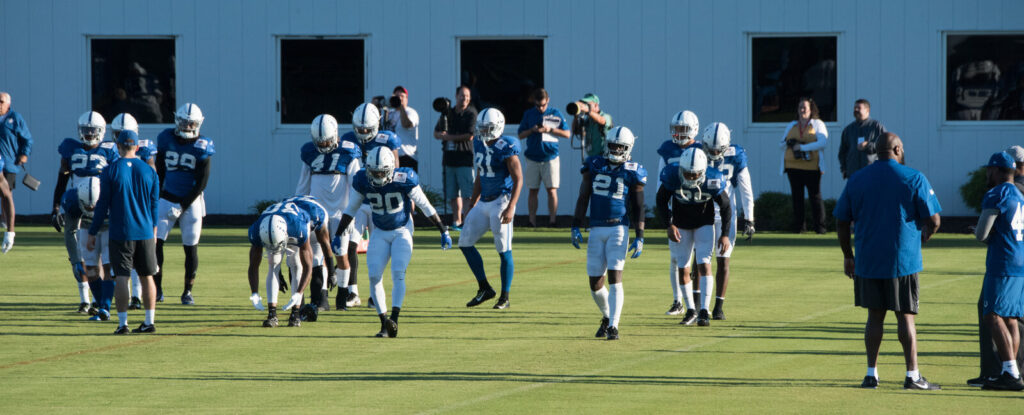 NFL players in pads run through drills on the practice field during training camp