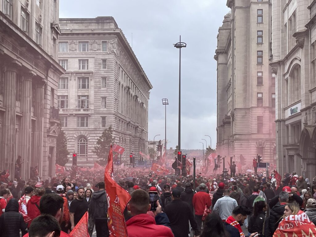 Liverpool FC supporters celebrating with red flares and flags during a title parade in Liverpool city centre