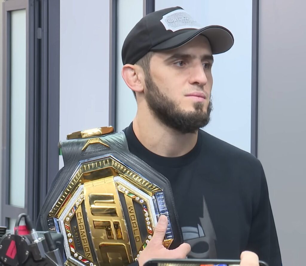 Islam Makhachev, close-up, wearing the UFC gold championship belt over his shoulder, sharp and clearly recognizable, photographed in 2022 after his first title win at UFC 280