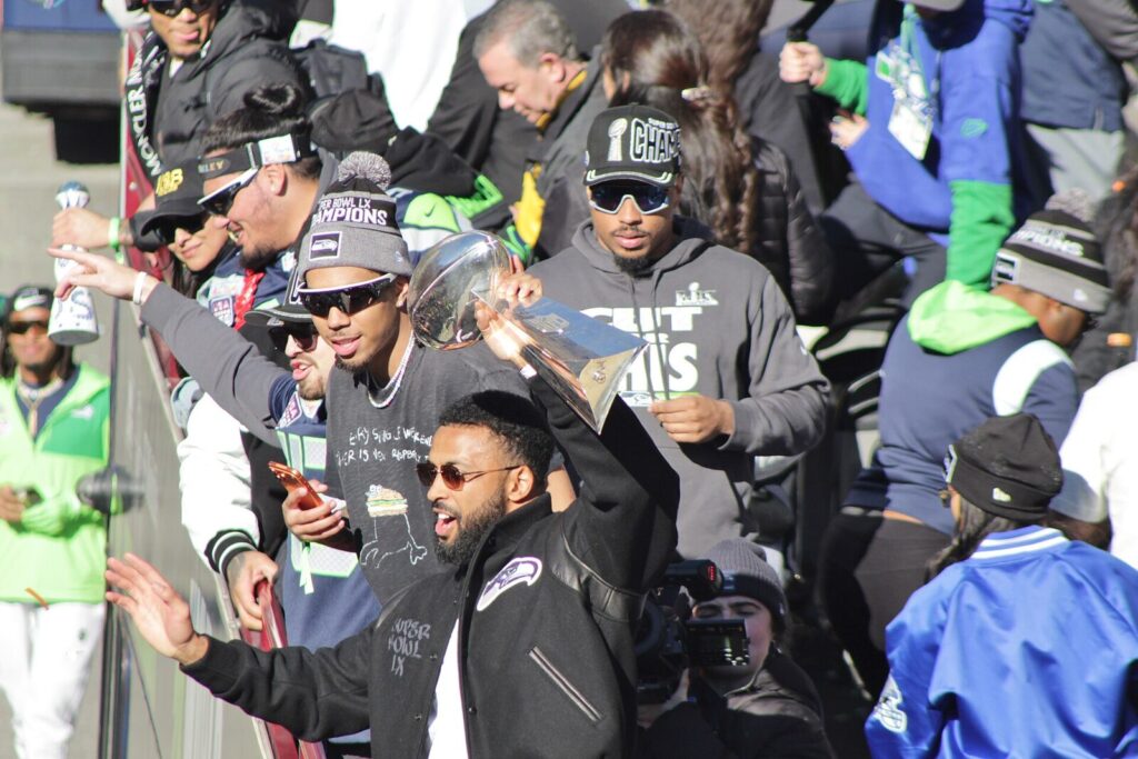 Seattle Seahawks players celebrate on a parade float after winning Super Bowl LX, one holding the Vince Lombardi Trophy (File photo: Seattle Seahawks' Super Bowl LX championship parade, 2026 (not from a Patriots matchup).)