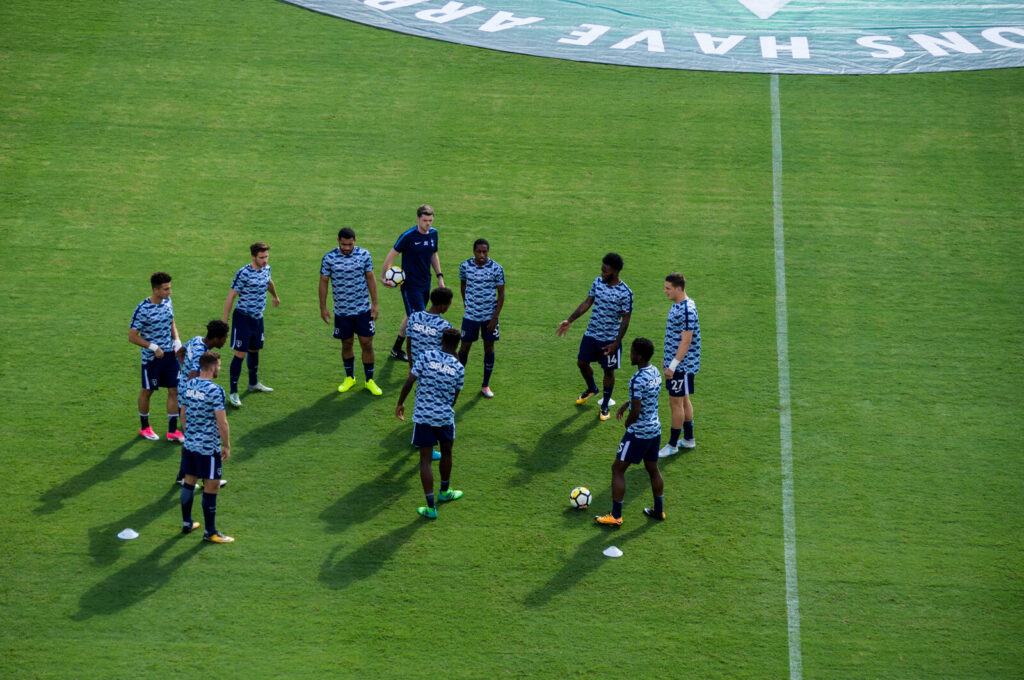 Tottenham Hotspur squad in training kits doing a passing drill on the pitch