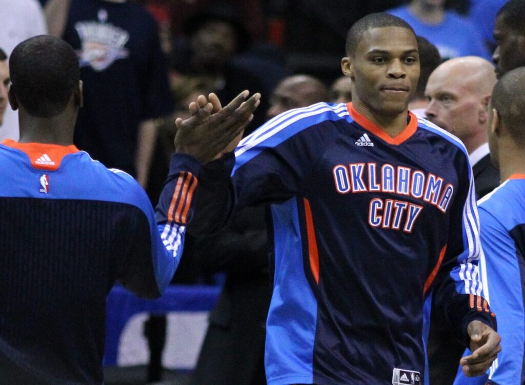 Russell Westbrook in an Oklahoma City Thunder jersey high-fiving a teammate courtside (Foto de arquivo: Russell Westbrook pelo Oklahoma City Thunder em 2011.)